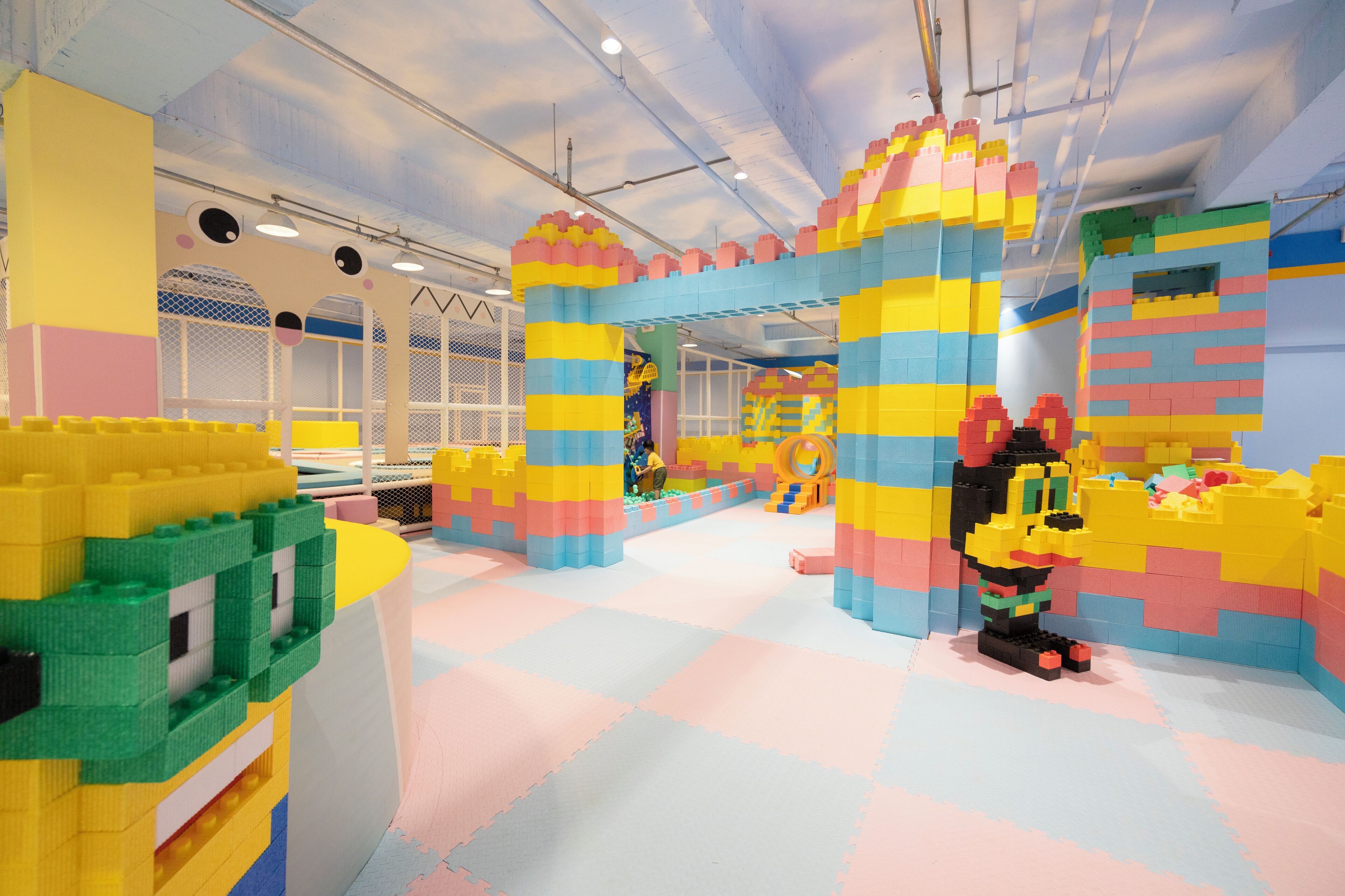 Un área de juegos con coloridas estructuras de LEGO y suelo acolchado.