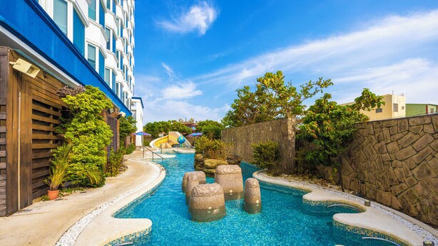 A swimming pool with stone steps and a wooden fence on one side. - Kenting Long Beach Hotel (Checheng)