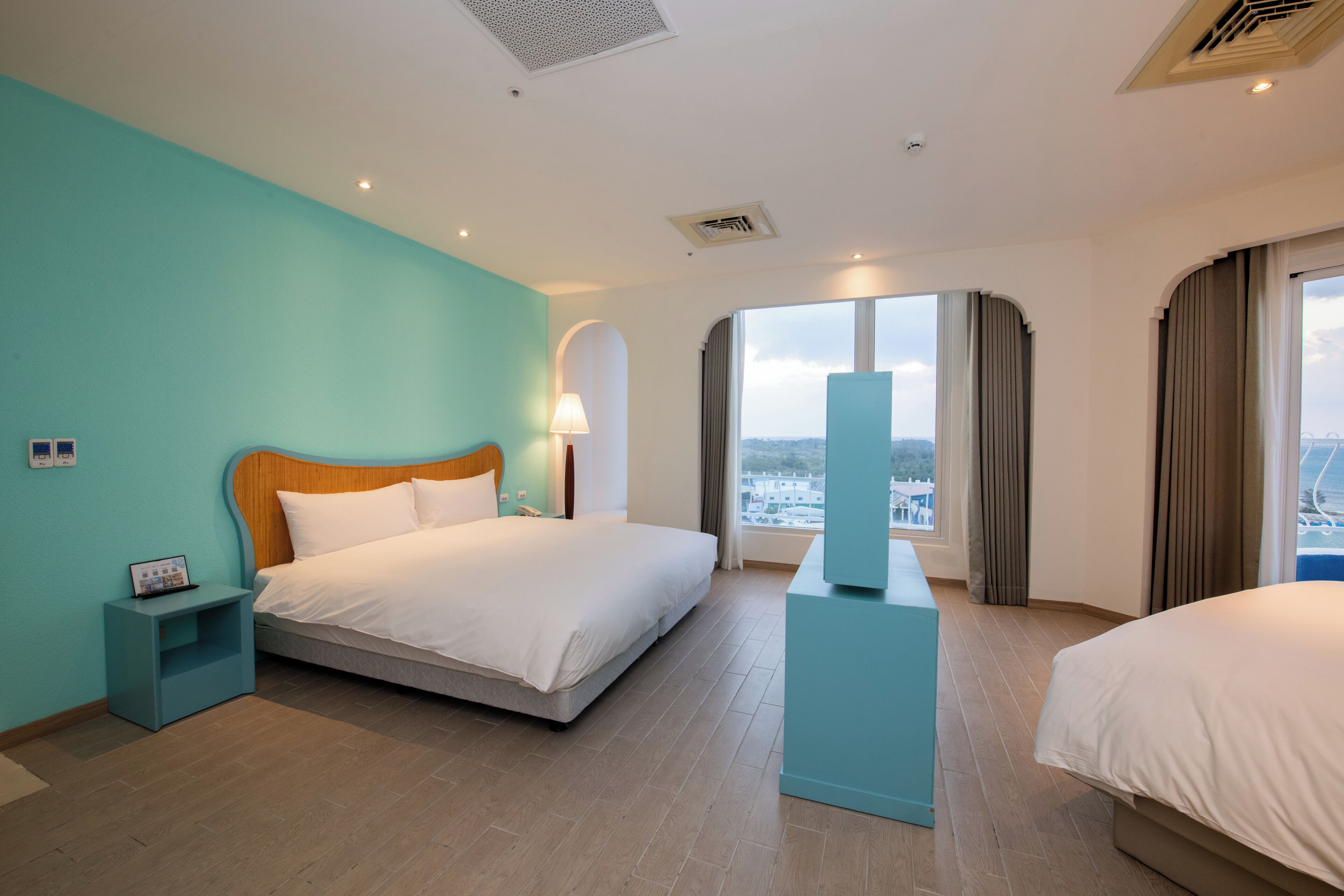 Una habitación de hotel con una cama grande, una mesita de noche, un escritorio pequeño y una ventana con vistas.