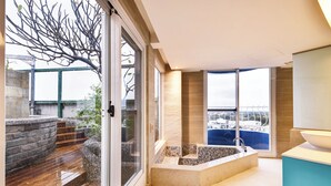 A modern bathroom with a bathtub, large windows, and a view of the city. - Kenting Long Beach Hotel (Checheng)