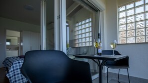 A modern room with a bed, a dining table with two chairs, and a glass of wine. - Flora relax house (Fažana)