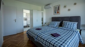 A bedroom with a bed, a nightstand, a wardrobe, and a bathroom visible through an open door. - Flora relax house (Fažana)