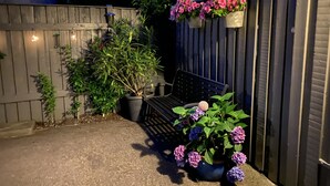 Ein Gartenbereich mit einer Bank, Blumentöpfen und hängenden Blumenkörben.