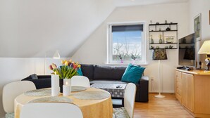 Ein gemütliches Wohnzimmer mit Esstisch, Sofa und Fernseher.
