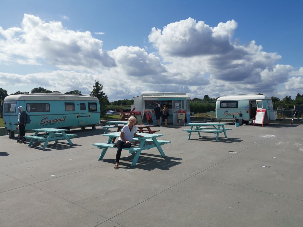 Un espace dédié aux food trucks, avec des tables de pique-nique et une personne assise à l’une d’elles.
