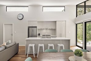 A modern kitchen with a central island, bar stools, and a dining table with chairs.
