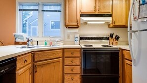 Une cuisine avec des meubles de rangement en bois, une cuisinière, un évier et un réfrigérateur.