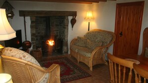 Un salon chaleureux, avec des meubles en osier, une cheminée et une porte en bois.
