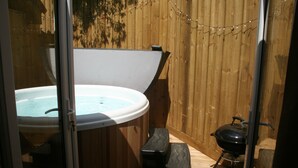 Un bain à remous et un barbecue installés dans une structure en bois.