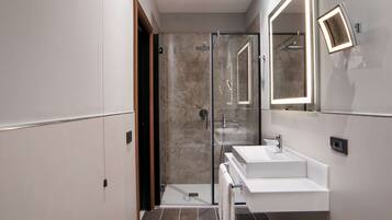 A modern bathroom with a glass shower, two sinks, and a large mirror.