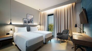 A modern hotel room with two beds, a desk, and a chair.