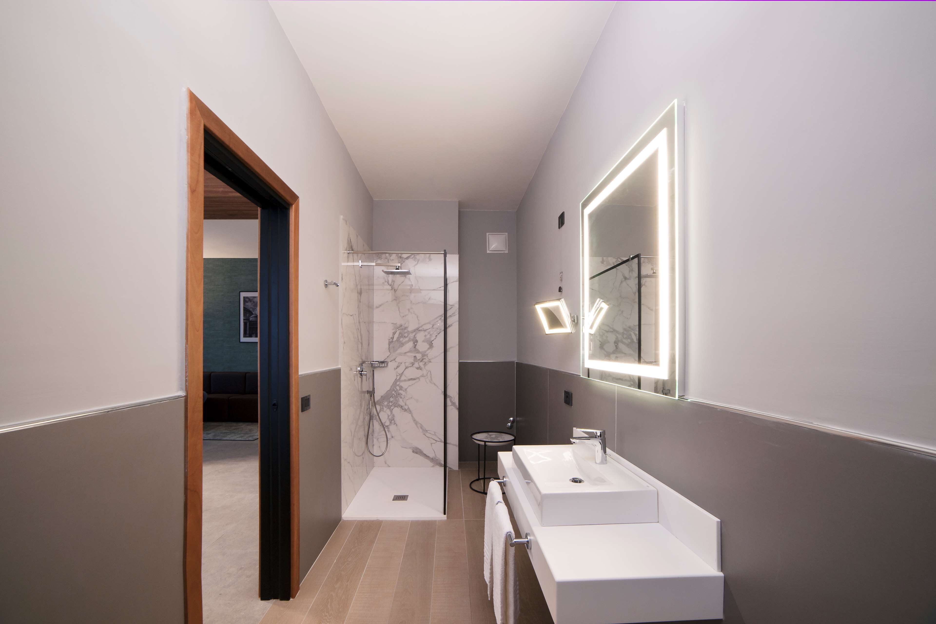 Une salle de bain moderne avec une douche à l’italienne, un grand miroir et un lavabo blanc.