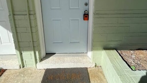 A closed door with a doormat in front, a mailbox to the right, and a light fixture above the door. - Sea Treasure - Only 2 blocks to the Beach (Cape Canaveral)