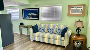 A living room with a sofa, a table, a lamp, and a picture on the wall. - Sea Treasure - Only 2 blocks to the Beach (Cape Canaveral)