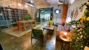 A spacious, industrial-style room with exposed ceilings, a wooden table, a sofa, and a variety of chairs.
