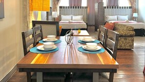A dining area with a wooden table set for four, surrounded by chairs.