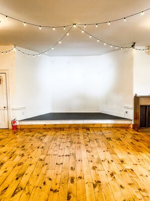 A room with wooden flooring, a white wall, and string lights.