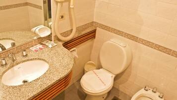 Un baño con lavamanos, inodoro, bidé y espejo.