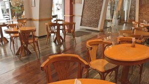 A restaurant interior with wooden tables and chairs, a brick wall, and a glass door leading outside. - Hotel Felipe II (Córdoba)