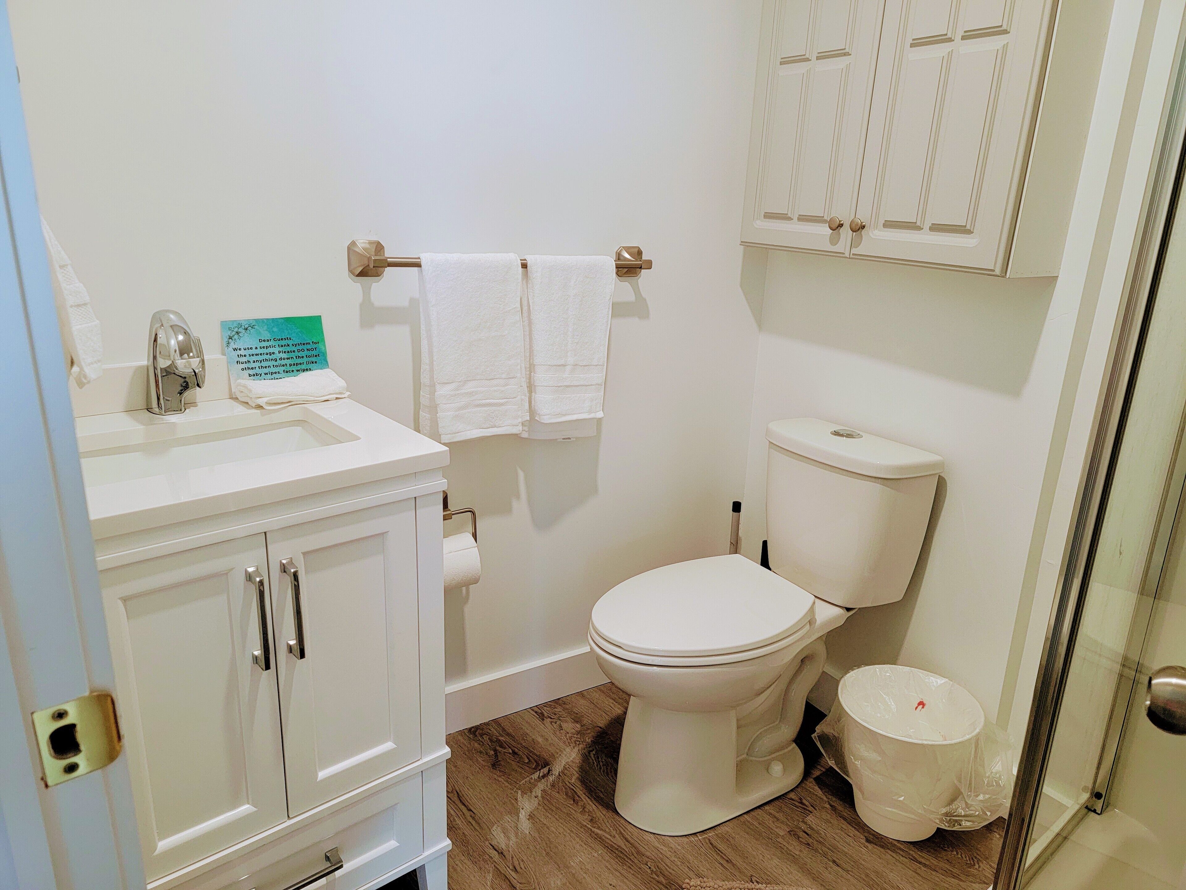 A bathroom with a toilet, sink, and cabinets.