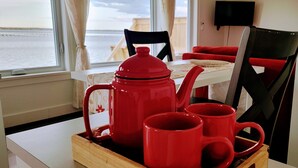 A dining area with a table, chairs, and a tray with red mugs and a teapot. - Cabin on the clouds. (Cocagne)