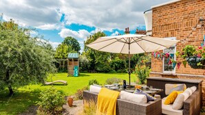 Un espace patio aménagé avec des meubles en osier, une table et un grand parasol.