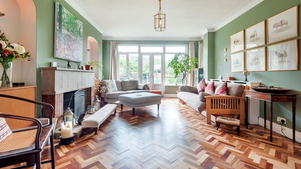 Un salon spacieux doté d’un parquet en point de Hongrie, d’une cheminée et d’une grande fenêtre.