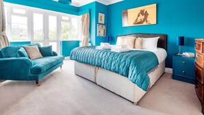 Une chambre à coucher avec un grand lit, un canapé bleu et une table de chevet.