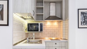 Une cuisine moderne dotée d’un four à micro-ondes encastré, d’un évier en acier inoxydable et d’armoires en bois.