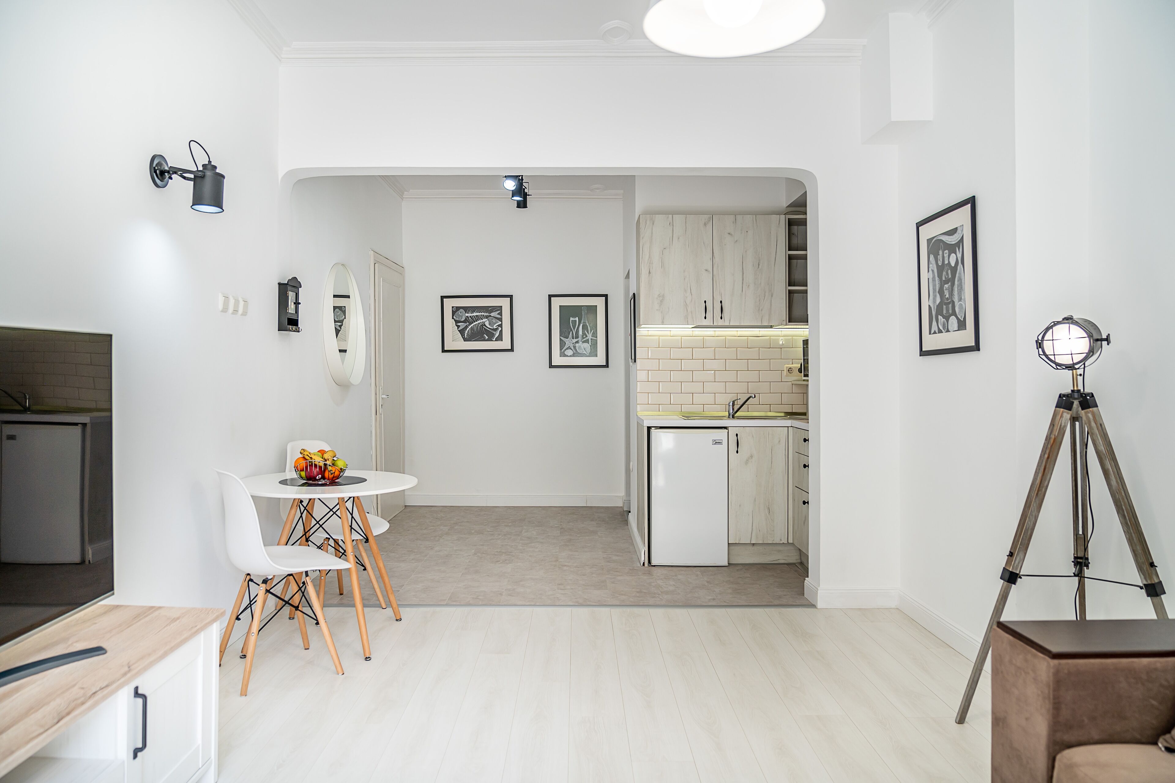 A modern kitchen with white cabinets, a white countertop, and a small dining area with a white table and chairs.