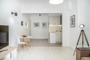 A modern kitchen with white cabinets, a white countertop, and a small dining area with a white table and chairs. - Luxury apARTment By The Sea + FREE PARKING+HBO+Netflix (Varna)