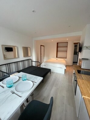 Een compacte kamer met een eethoek, een bed en een kitchenette.
