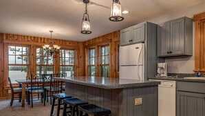 A kitchen with wooden cabinets, a refrigerator, a coffee maker, and a bar area with stools.