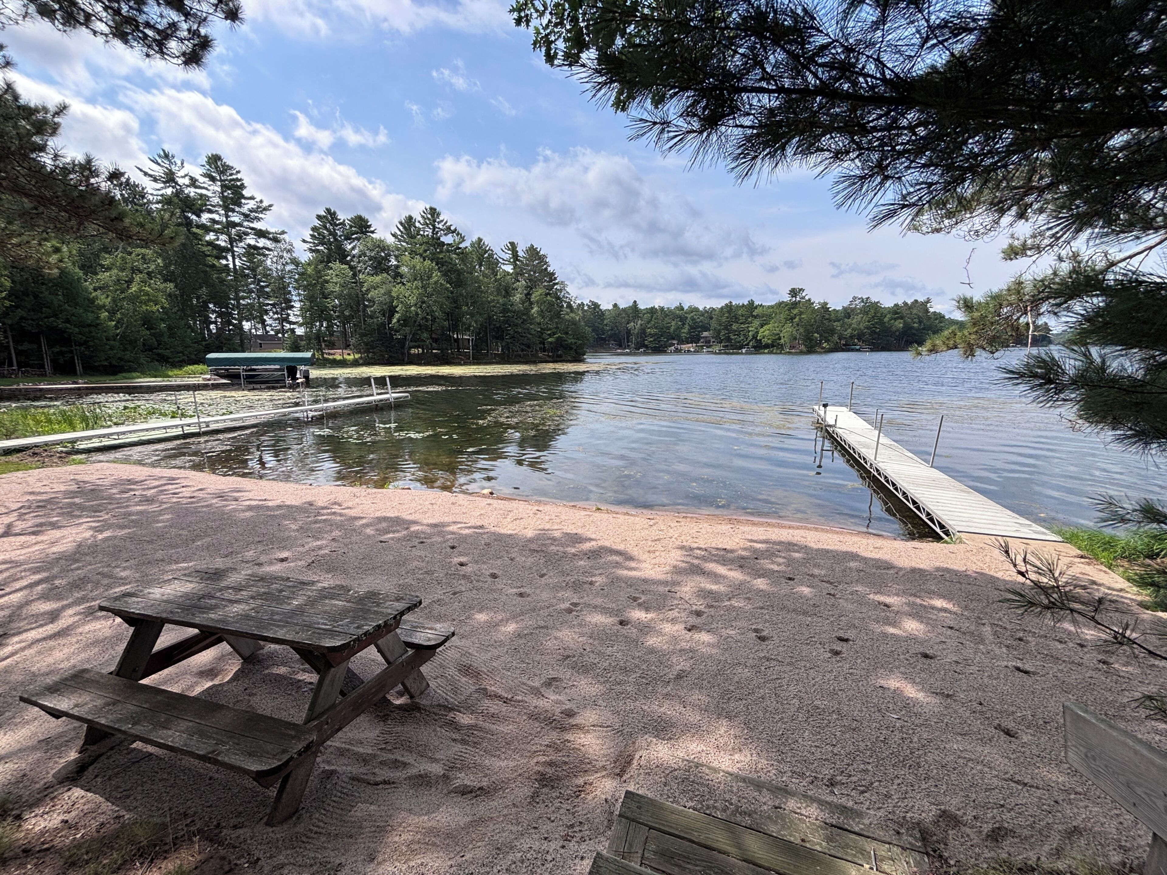 A lakeside picnic area with a bench and a dock extending into the water.