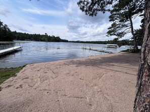 Un lac paisible avec une jetée qui s’avance sur l’eau, entouré d’arbres et sous un ciel dégagé.