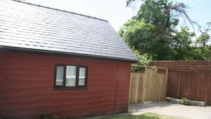 A red building with a sloped roof and a window with blinds. - The Nook - Farm Park Stay with Hot Tub, BBQ & Fire Pit (Swansea)