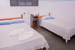 Une chambre avec deux lits simples, un bureau avec une chaise et une fenêtre avec des stores.