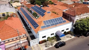 Un bâtiment doté de plusieurs panneaux solaires sur le toit, d’un espace de stationnement et d’un petit jardin.