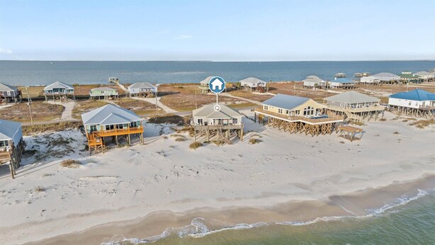 Une propriété située en bord de mer, comprenant plusieurs maisons, dont certaines sont surélevées sur pilotis, et offrant une vue dégagée sur l’océan.