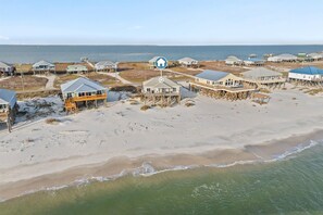 Une propriété située en bord de mer, comprenant plusieurs maisons, dont certaines sont surélevées sur pilotis, et offrant une vue dégagée sur l’océan.