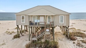 Une maison de plage dotée d’une terrasse en bois et d’une seule étage.