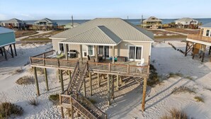 Une maison située en bord de mer, dotée d’une terrasse et d’un escalier menant au bâtiment principal.