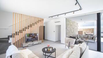 A modern living room with a staircase, a sofa, a coffee table, and a stone wall.