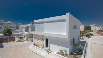 A modern two-story house with a flat roof, large windows, and a stone foundation.