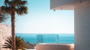 Zona relax esterna moderna con balaustra in vetro che si affaccia su una vista costiera.