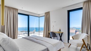 Camera d'albergo moderna con un letto grande, una scrivania e una sedia, con un balcone vista mare.