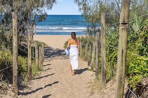 A pathway leading to the beach with wooden posts and wire fencing.