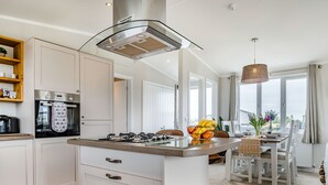 Une cuisine moderne dotée d’un îlot central, d’un four encastré et d’un coin repas offrant une vue agréable.
