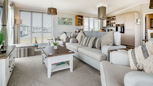 Un salon moderne avec un canapé, une table basse et un coin cuisine à l’arrière-plan.