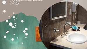 Habitació d'hotel amb un llit, una tauleta de nit amb un telèfon i un bany amb un vàter i un mirall.